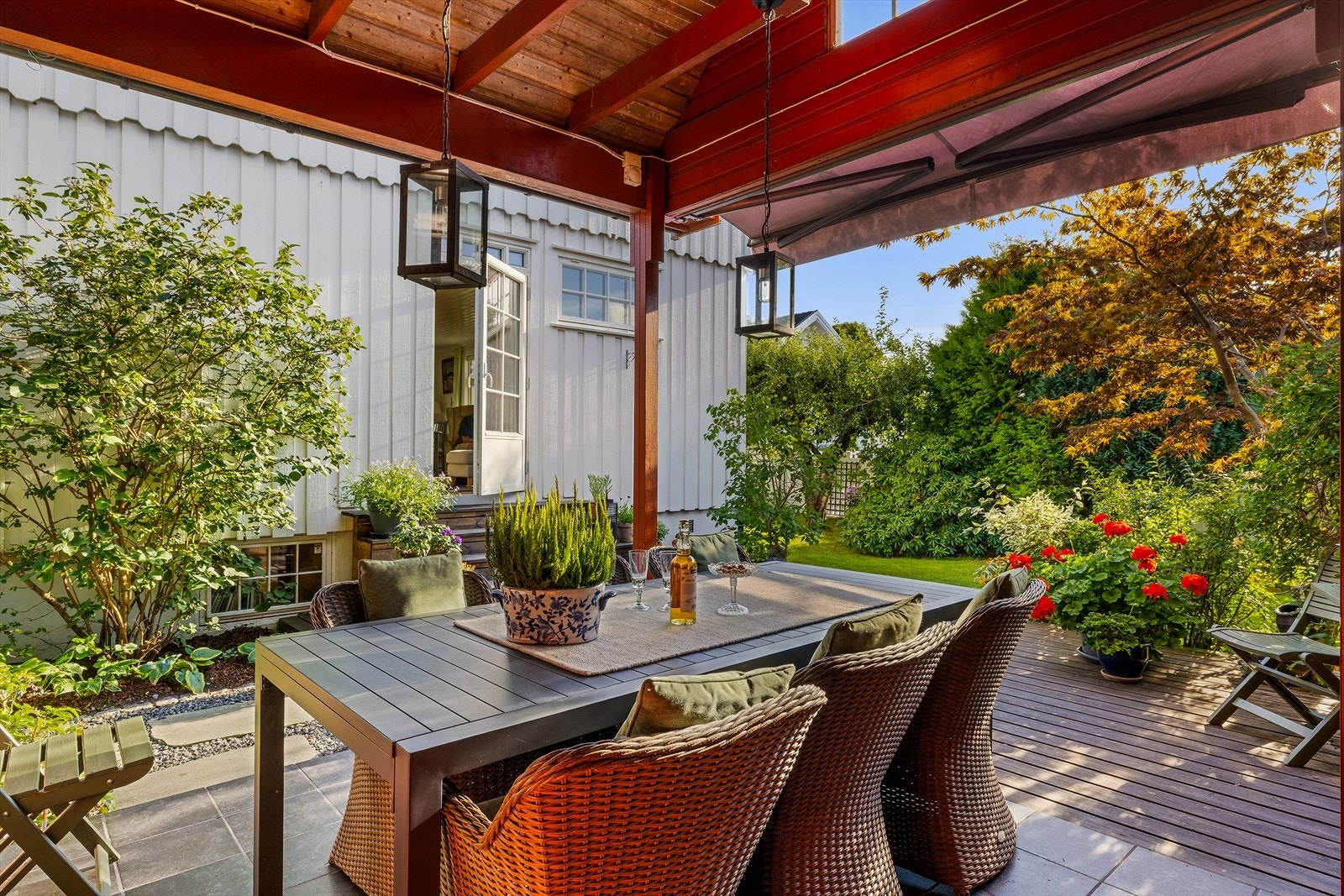 Utgang fra stue til 33 m² markterrasse med impregnerte gulvbord og støpt plate med fliser. Del av terrassen har overbygd tak og peis. Markise Galleribilde