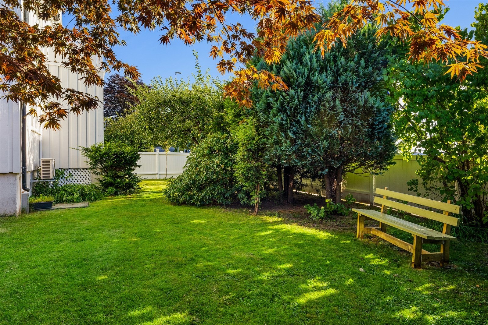 Frodig, skjermet og velstelt hage med rododendron, stauder og annen beplantning som gir farger og liv gjennom sesongen Galleribilde