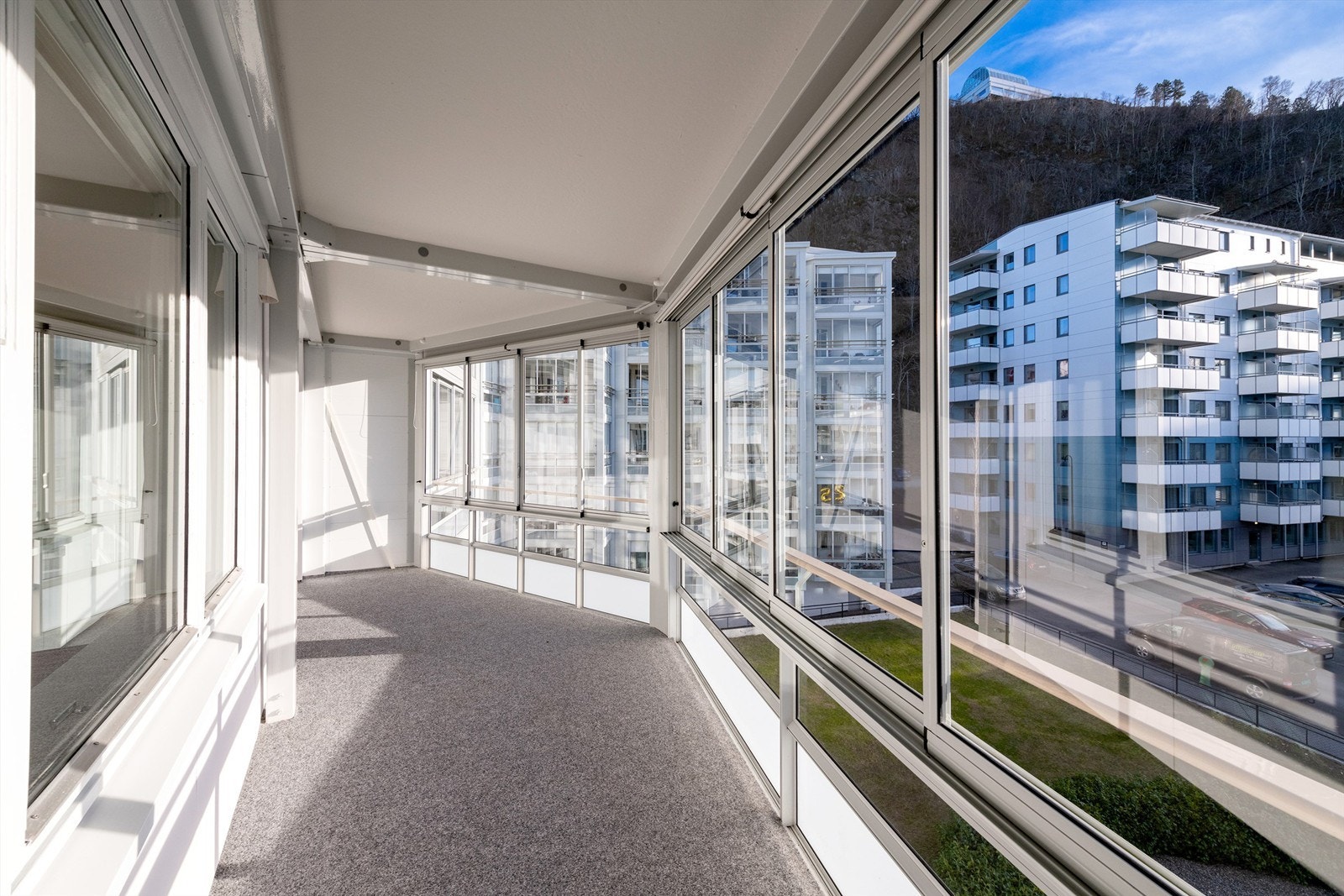 Innglasset balkong med vegg til vegg teppe på gulv. Det er stikkontakt på balkongen Galleribilde
