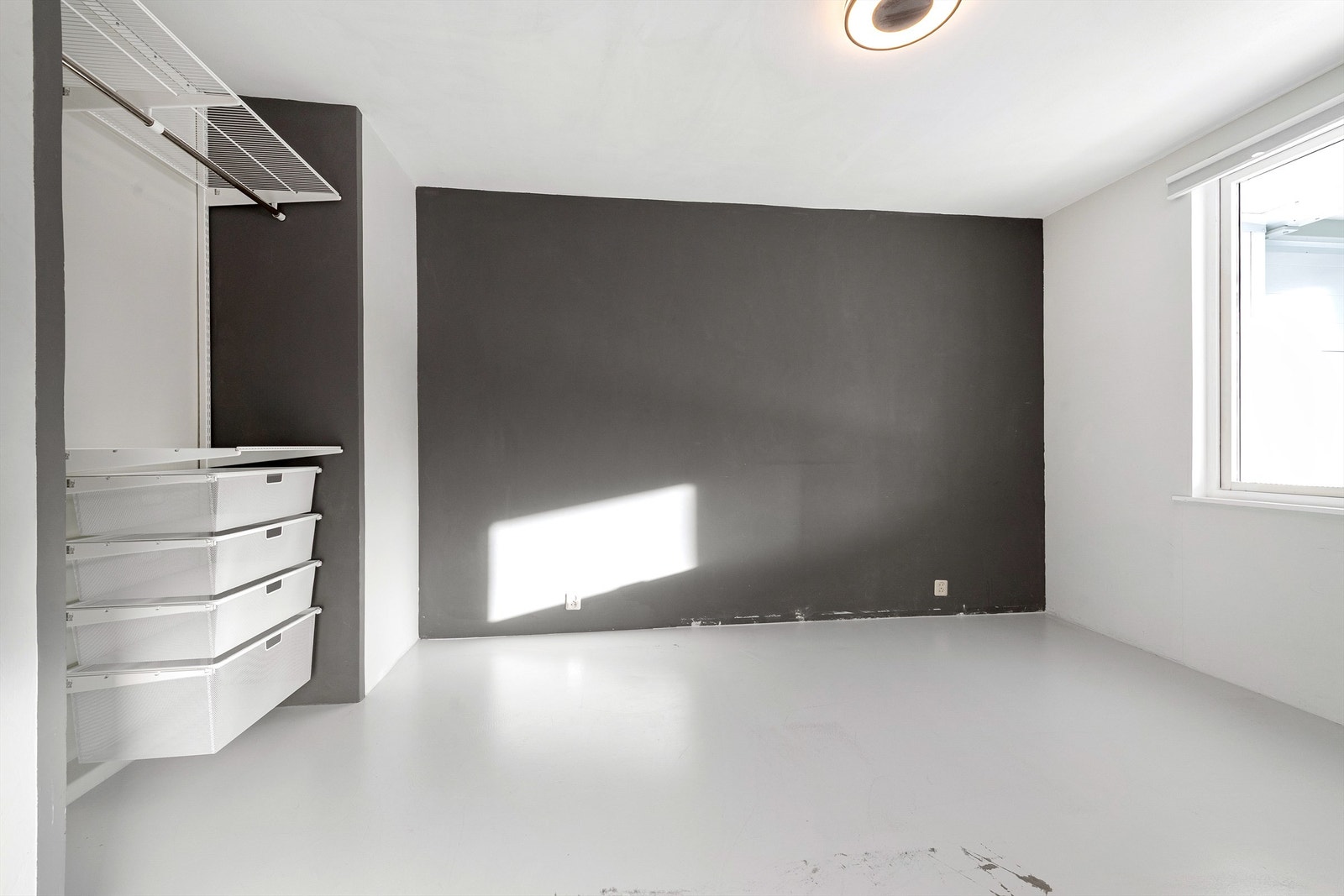 Soverom med malt betonggulv og åpen garderobeinnredning Galleribilde