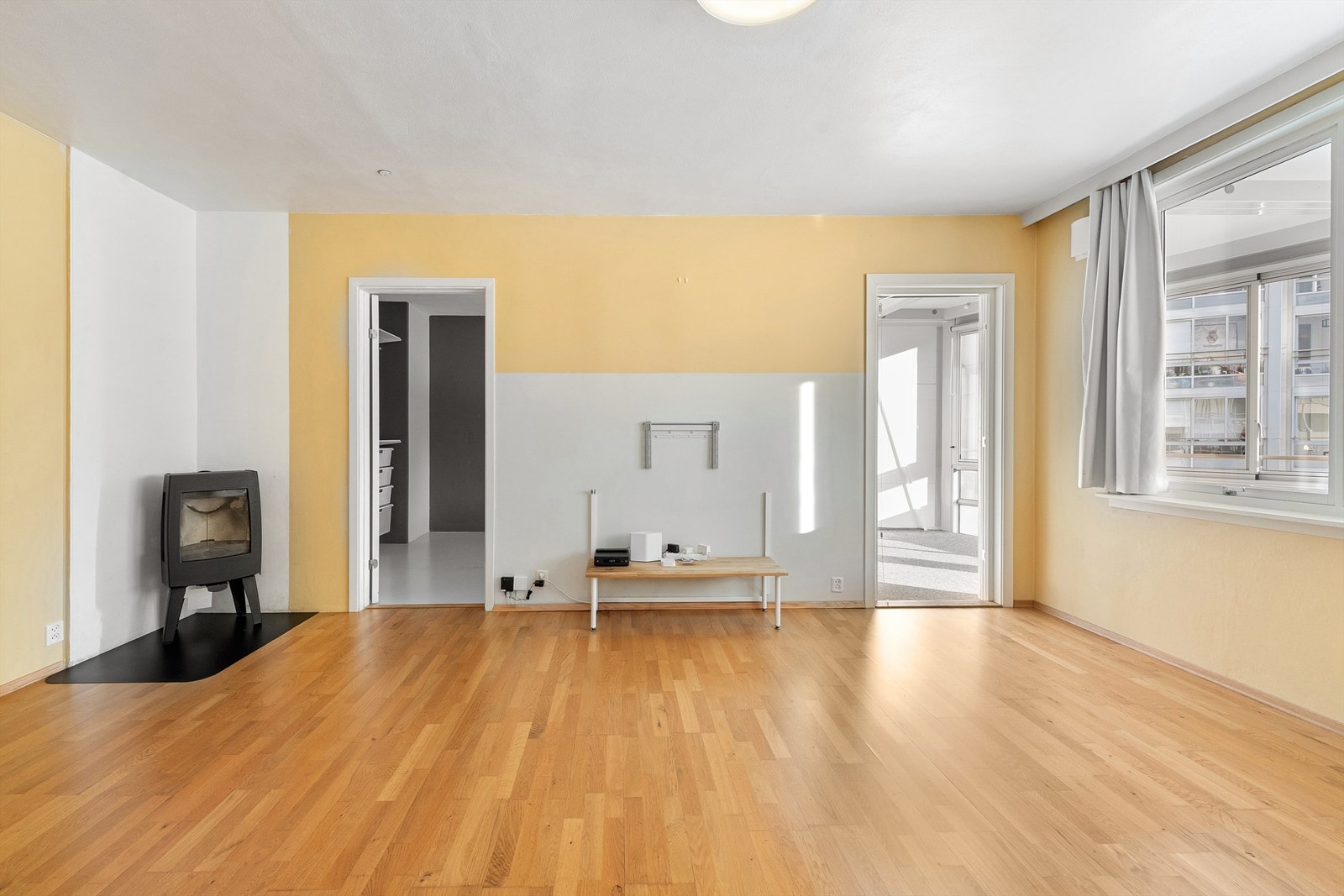 Lys stue med peisovn. Adkomst til soverom samt utgang til innglasset balkong Galleribilde