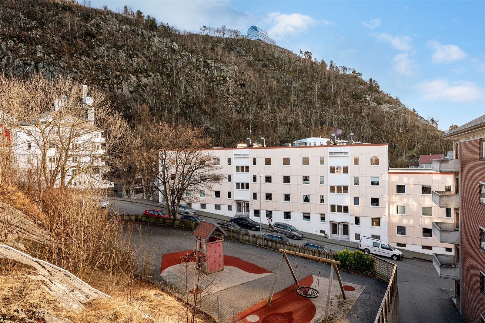 Fasade av borettslaget sett fra nord med lekeplass like ved og nærhet til byfjellet Aksla Galleribilde