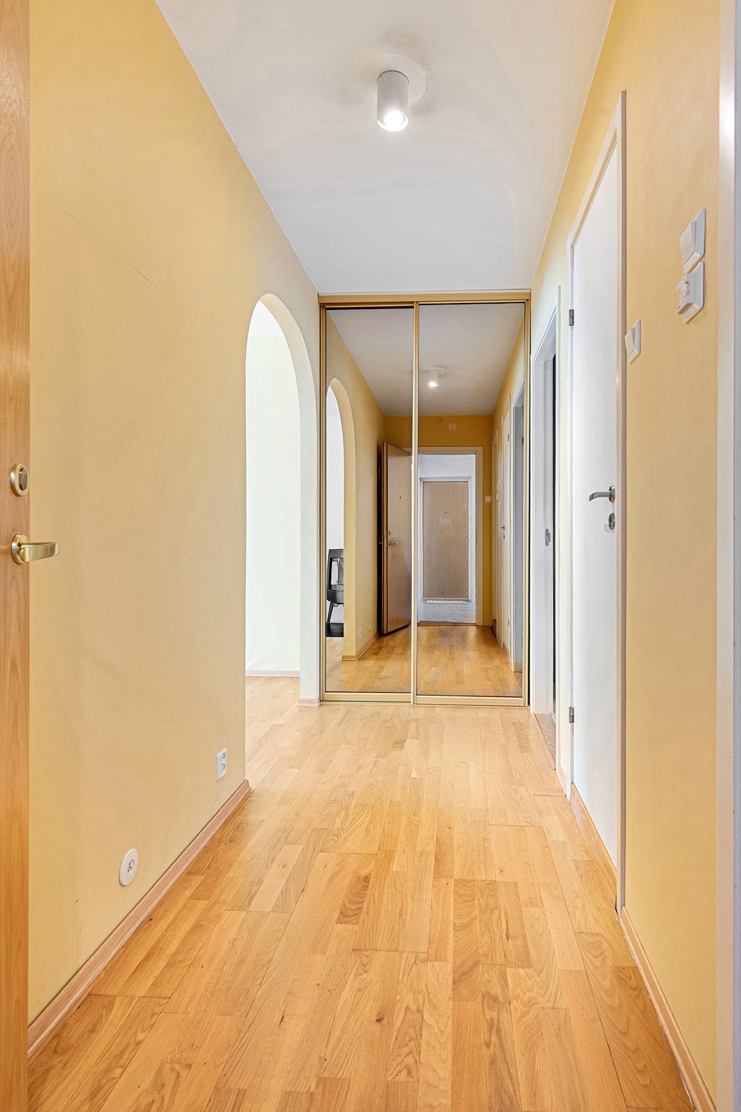 Gang med lyse overflater og skyvedørsgarderobe med speilfronter. Hvite glatte innerdører Galleribilde