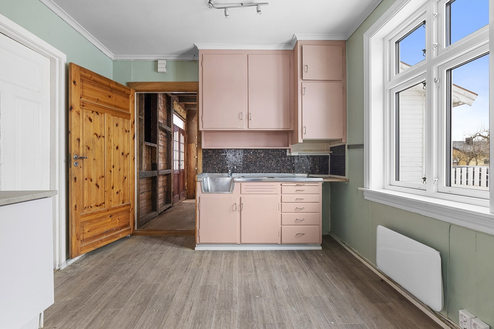 Kjøkken har eldre plassbygget kjøkkeninnredninger med benk av rustfritt stål Galleribilde