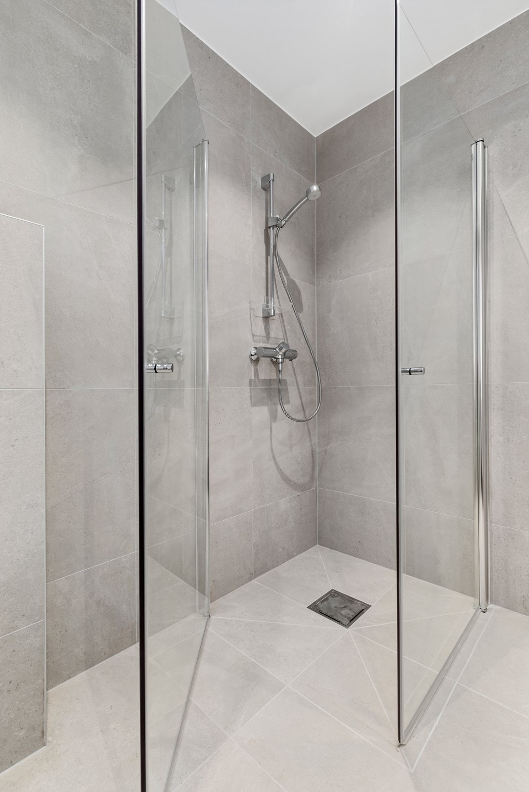 Helfliset bad med 60*60 flis, vegghengt toalett, stor dusjnisje og praktisk baderomsinnredning. Galleribilde