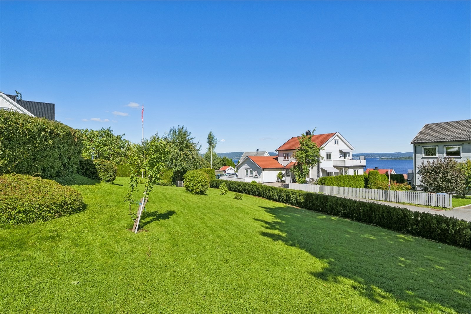 Fra verandaen er det enkel adkomst til den flotte hagen. Tomten er delvis innrammet av pen og frodig hekk, og det kan fremheves at ca. 45 meter hekk ble etablert mot Bilet i 2022. Galleribilde