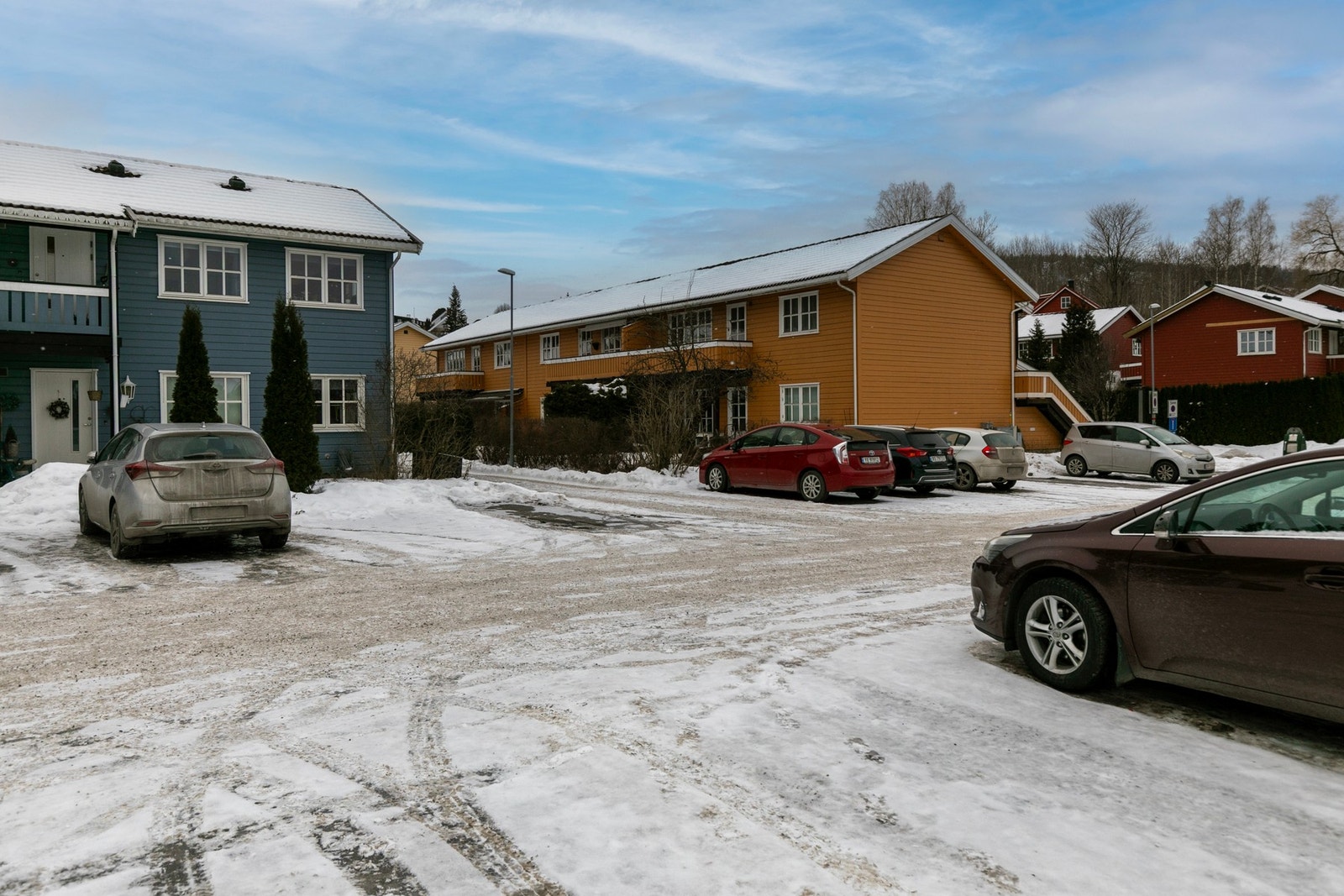 Parkeringsplassen(rød bil) ligger har en god intern beliggenhet i forhold til leilighetens plassering Galleribilde