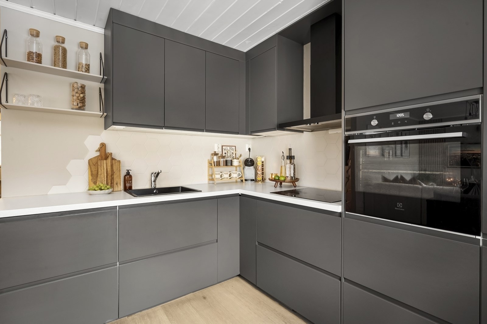 Kjøkkeninnredning med glatte fronter, hexagon-fliser på veggen over kjøkkenbenk og benkeplate i laminat. Galleribilde