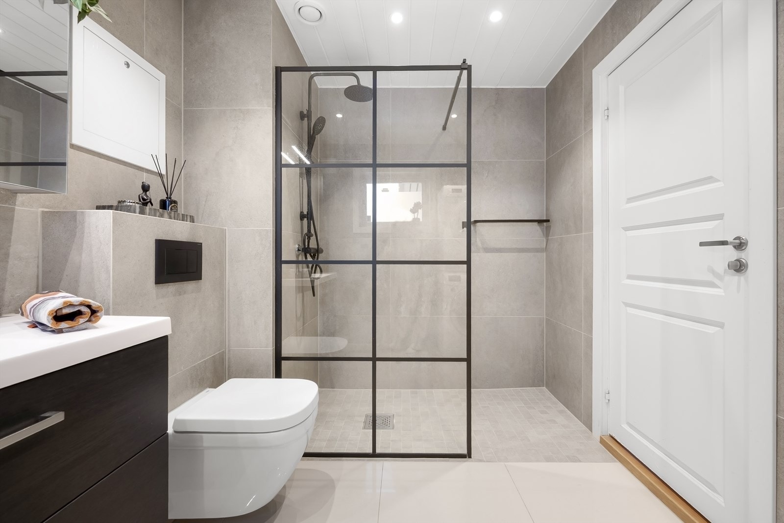 Badet er innredet med vegghengt toalett, stor dusjnisje med glassfelt og baderomsinnredning med skuffer, servant nedfelt i innredning og speilskap med lys. Galleribilde