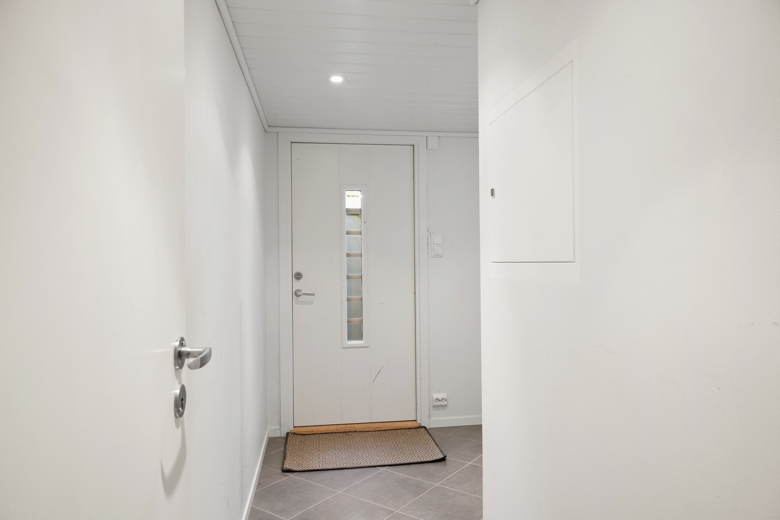 Lys og ryddig entré med flislagt gulv og plass til yttertøy og sko. Galleribilde