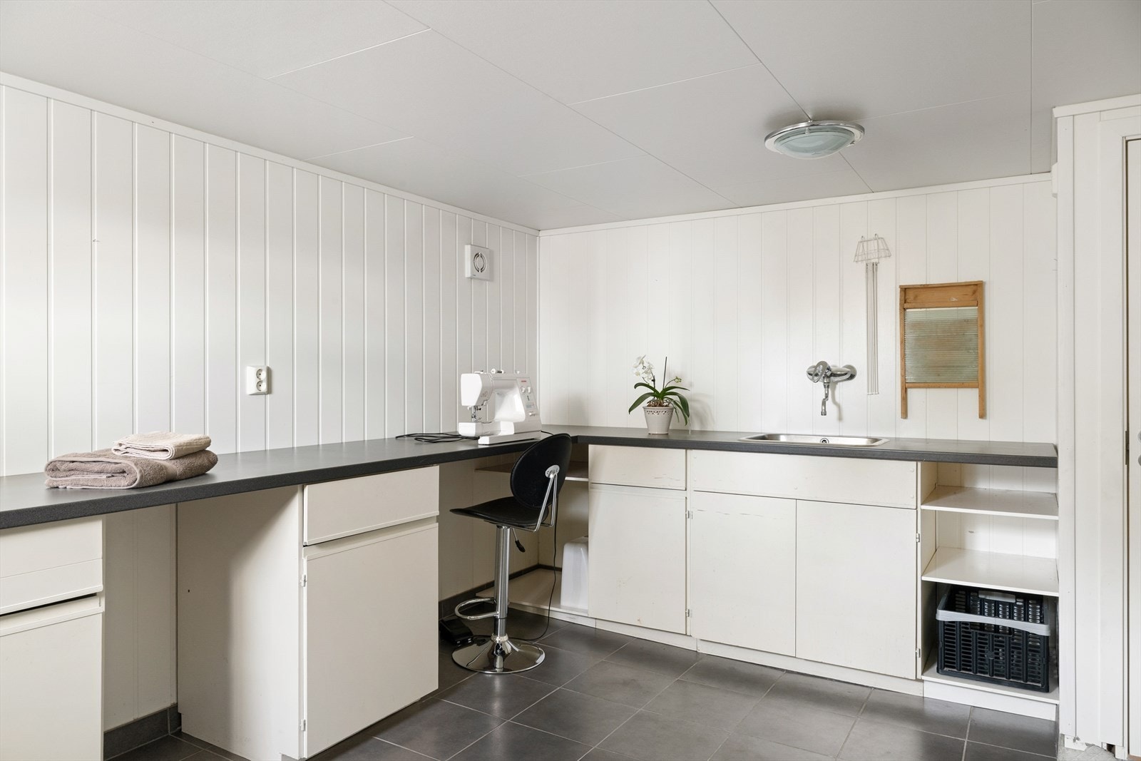 Funksjonelt vaskerom med lange benker, oppbevaringsløsninger og plass til både klesstell og annet praktisk arbeid. Galleribilde