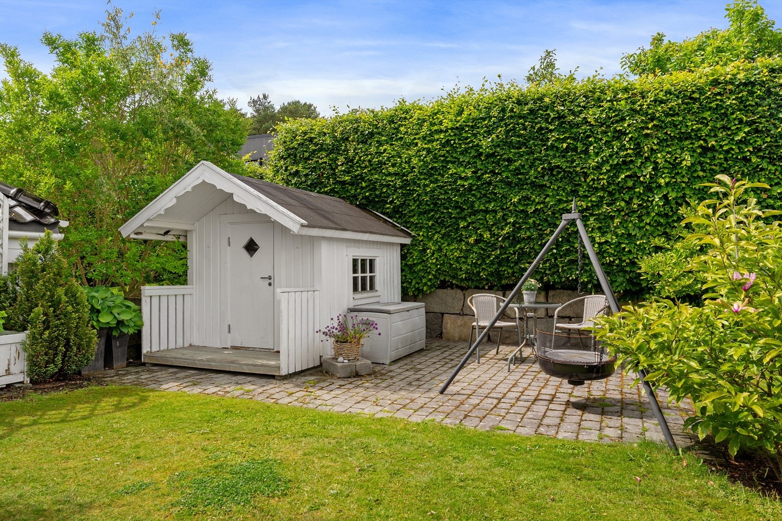 Hyggelig uteplass med brostein, sittegruppe og skjermende hekk - en lun og privat hagekrok. Galleribilde