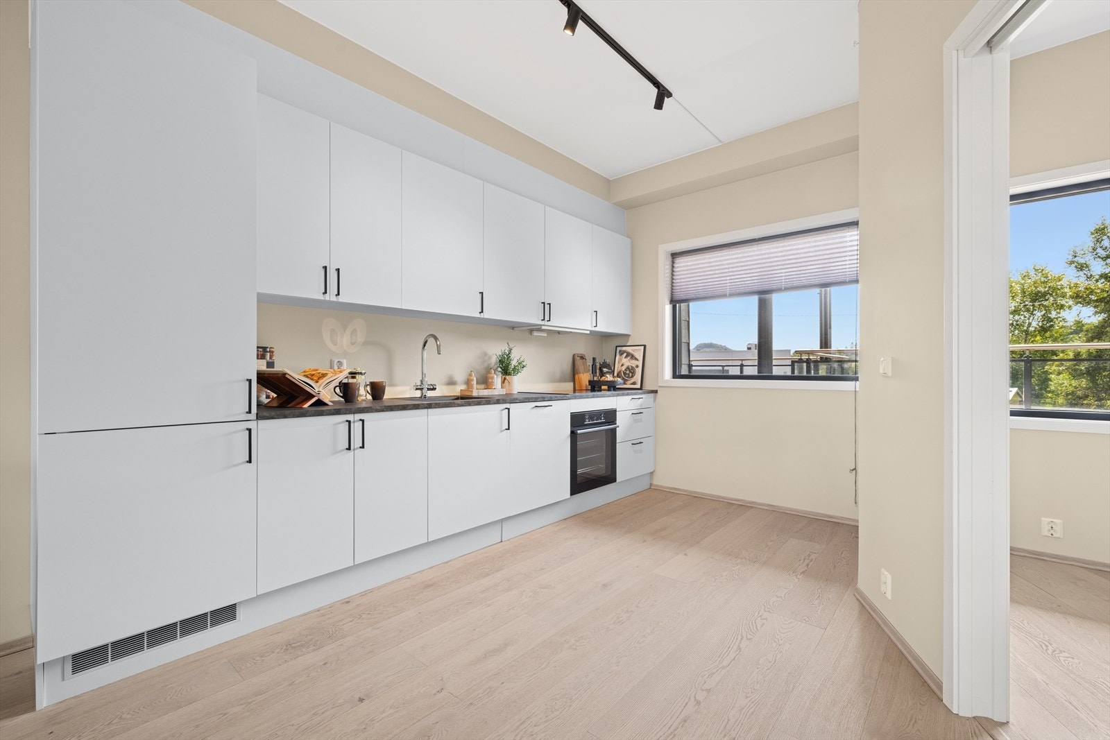 Moderne og pen kjøkkeninnredning med tidsriktige lyse fronter levert av Designa med integrerte hvitevarer. Galleribilde