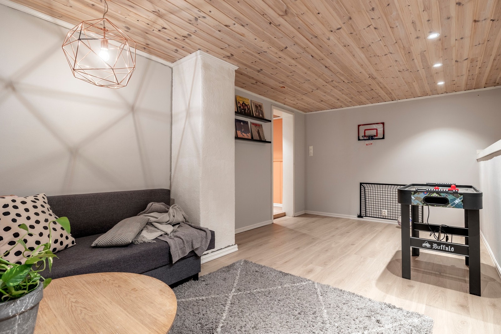 I kjelleretasjen ligger en hyggelig TV-stue med gråmalte vegger, laminatgulv og downlights. TV-stuen fungerer utmerket som et ekstra samlingssted for familien eller som en egen sone for barna. Her er det god plass til sofagruppe og TV-anlegg, perfekt for Galleribilde