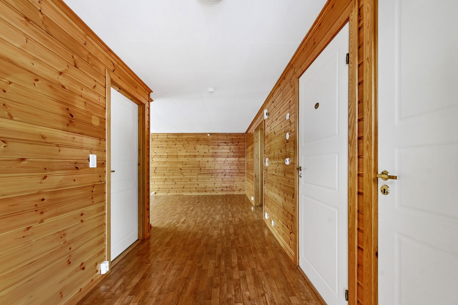 Gjennomgående panelvegger og malte tredører binder rommene sammen. Galleribilde