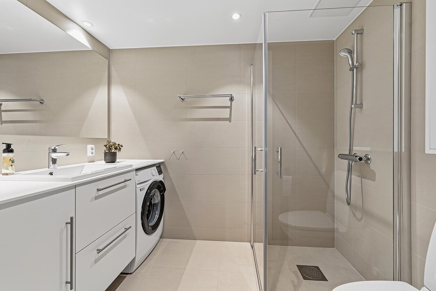 Delikat, flislagt baderom med vaskemaskin. Galleribilde