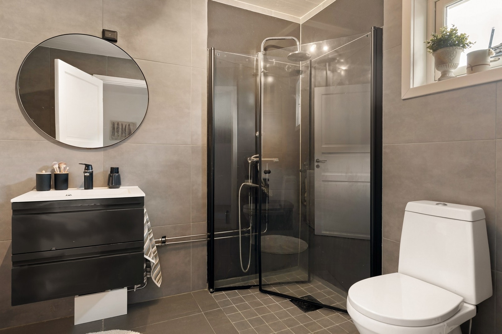 Flislagt bad med baderomsinnredning, dusjnisje, gulvmontert klosett og
uttak for vaskemaskin. Galleribilde