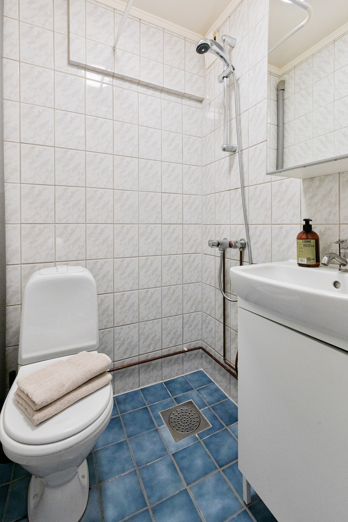 Funksjonelt og praktisk bad, innredet med dusj med forheng, gulvmontert toalett og baderomsinnredning med nedsenket servant og speilskap. Galleribilde