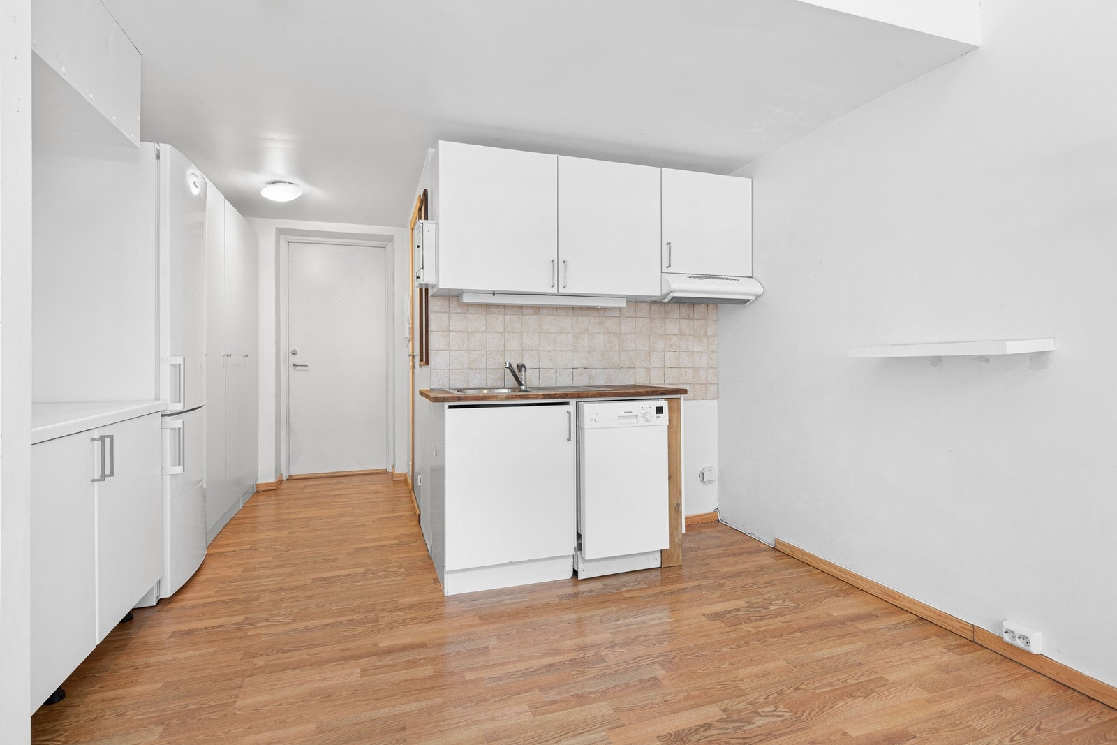 Kjøkkeninnredningen er enkel, med hvite, glatte fronter, laminert benkeplate og nedfelt oppvaskkum. Galleribilde