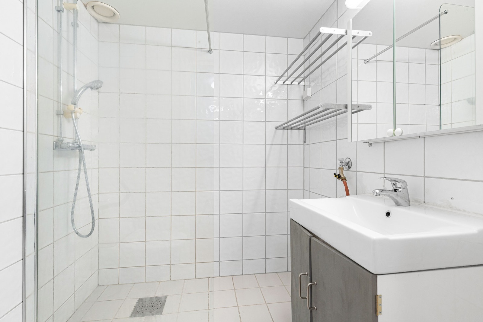 Badet er innredet med hvite fliser, varmekabler og opplegg for vaskemaskin. Galleribilde