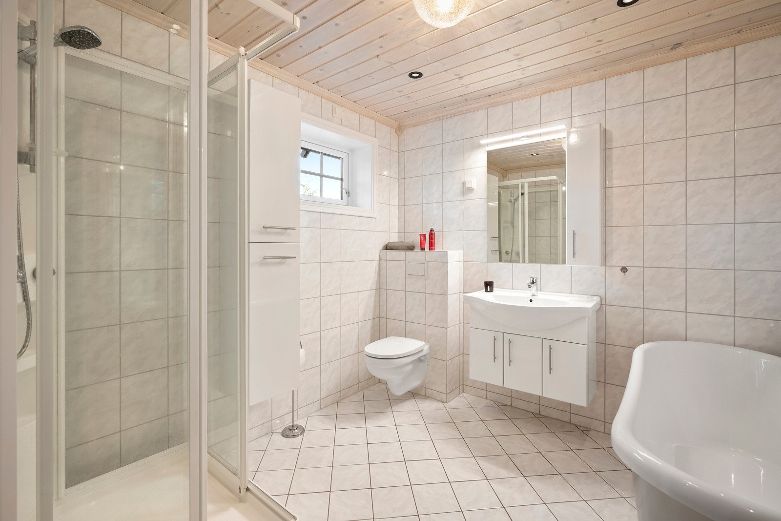 Boligen har et lekkert bad med paneltak med downlights og fliser på både vegger og gulv, samt elektriske varmekabler. Galleribilde