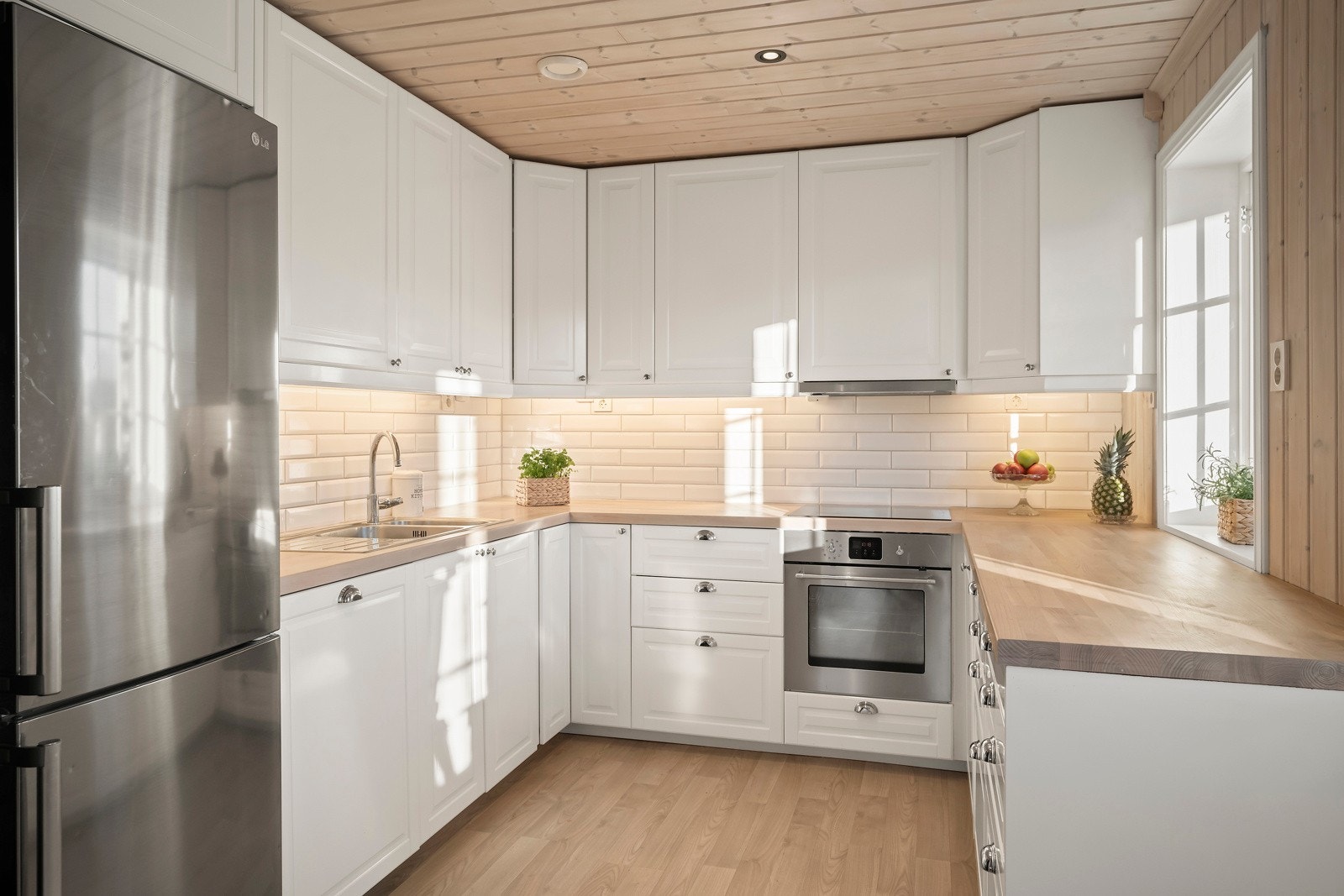 Kjøkkenet har innredning med lyse profilerte fronter og benkeplater av heltre med nedfelt kum. Galleribilde