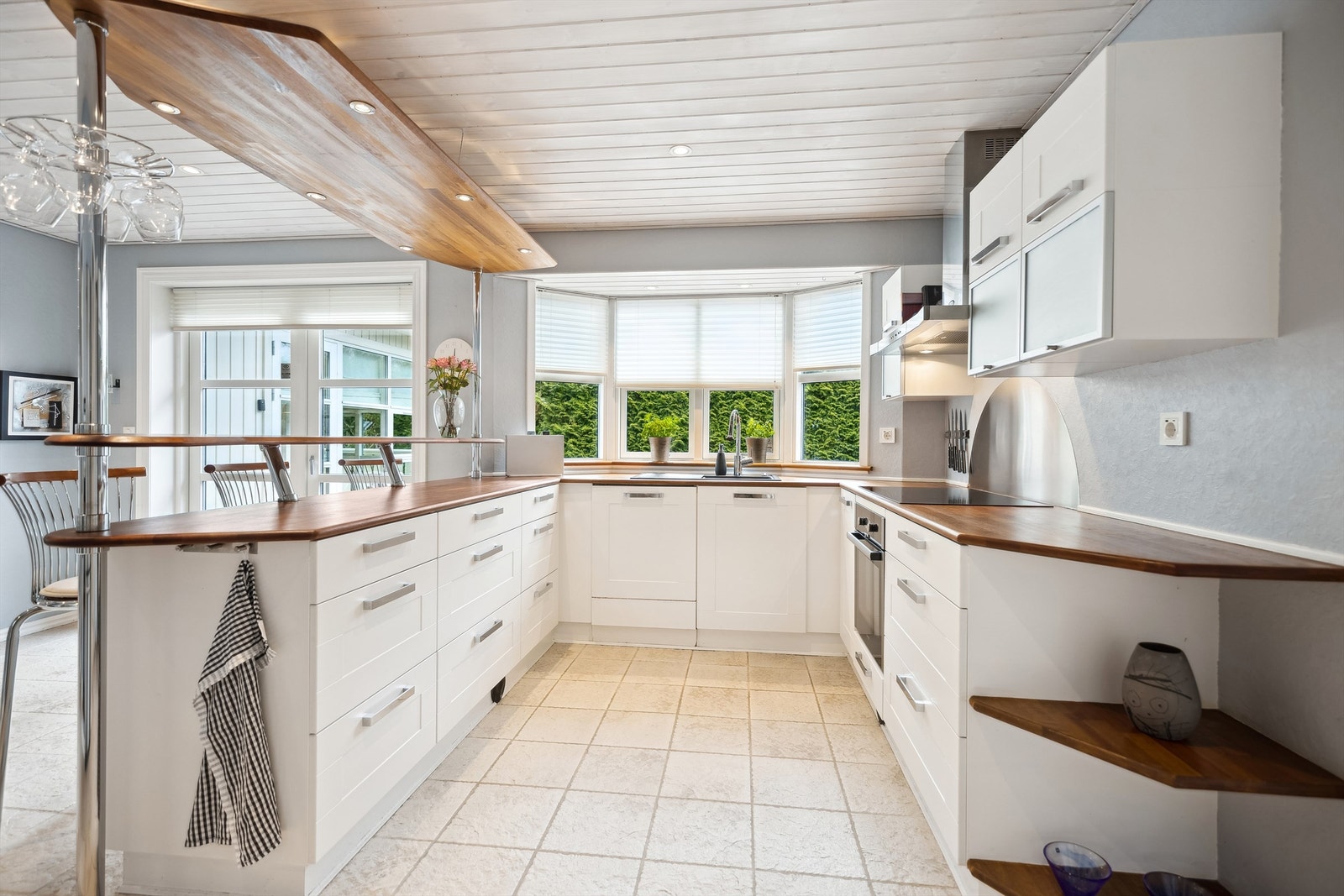 Lyst og tidløst kjøkken med integrerte hvitevarer som induksjonstopp, stekeovn og oppvaskmaskin. Galleribilde