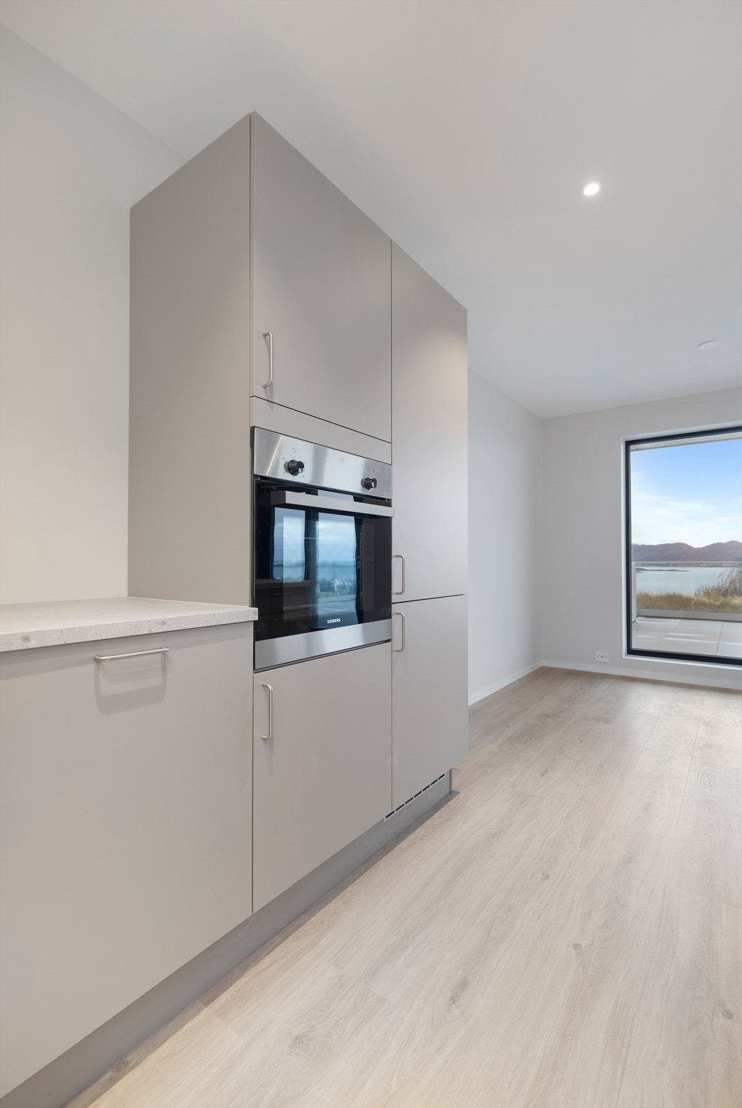 Kjøkkenet har slette fronter, intergrerte hvitevarer og stor kjøkkenøy med koketopp og nedfellt ventilator. Galleribilde