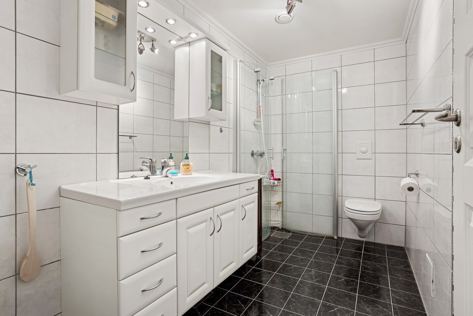 Flislagt baderom i underetasjen med keramiske fliser på vegger og gulv, samt malt platekledning i tak. Vannbåren gulvvarme gir behagelig komfort. Badet er innredet med vegghengt toalett, dusj med glassfoldedør, servant med møblement, speil og belysning. Galleribilde