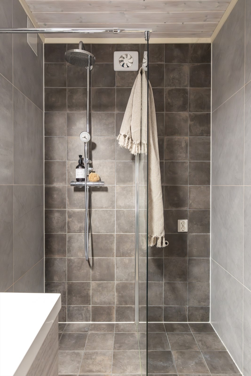 Innredningen består av et stort servantskap med heldekkende servantplate, belyst speilskap, toalett og opplegg for vaskemaskin. Videre er det en stor dusjnisje med glassdør og regnfallsdusj. Galleribilde