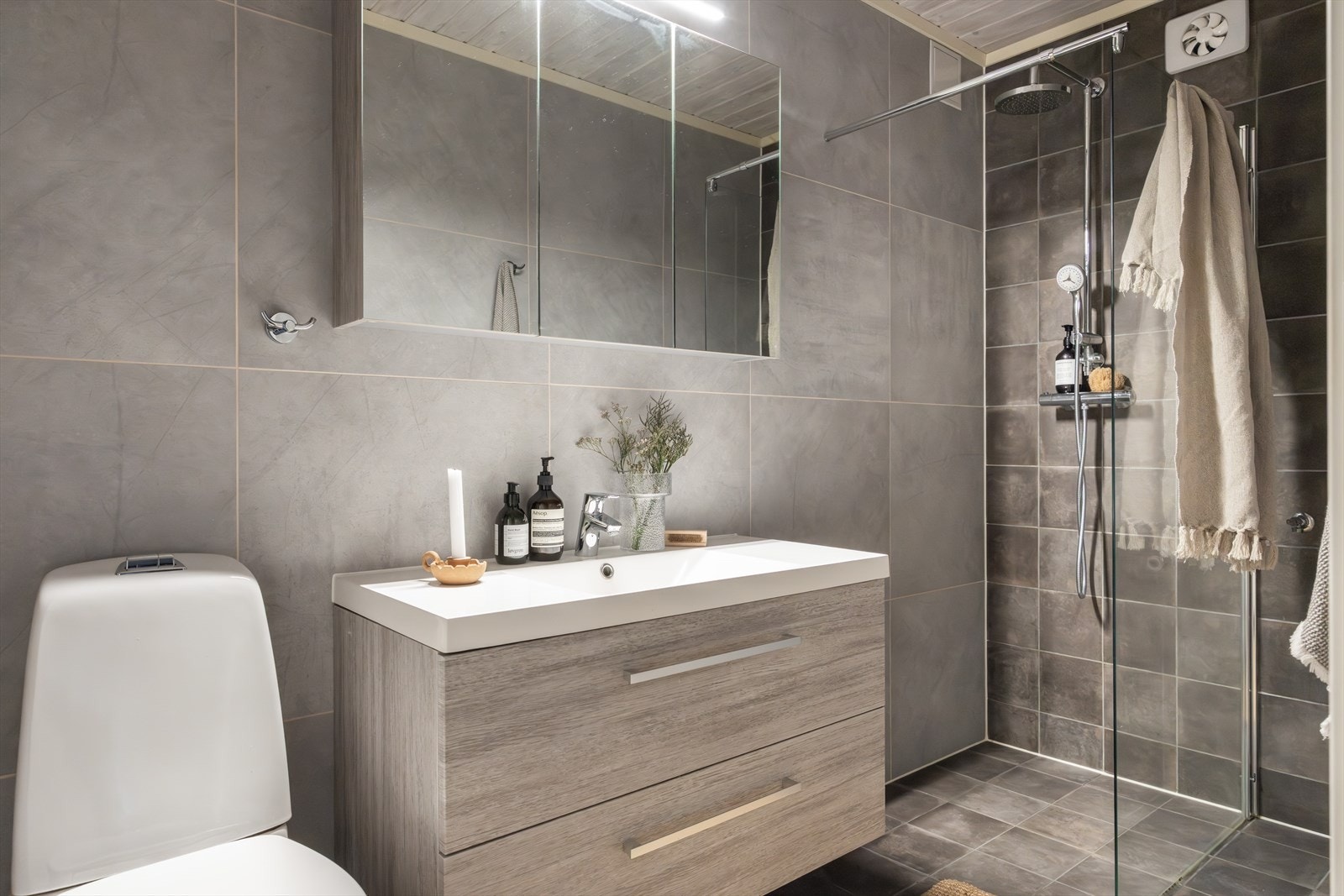 Det øvrige badet er et kombinert bad- og vaskerom som er lokalisert i underetasjen og ble pusset opp i 2017. Rommet har mørke fliser på gulvet med varmekabler, en kombinasjon av lyse og mørke fliser på veggene og malt panel i himling. Galleribilde