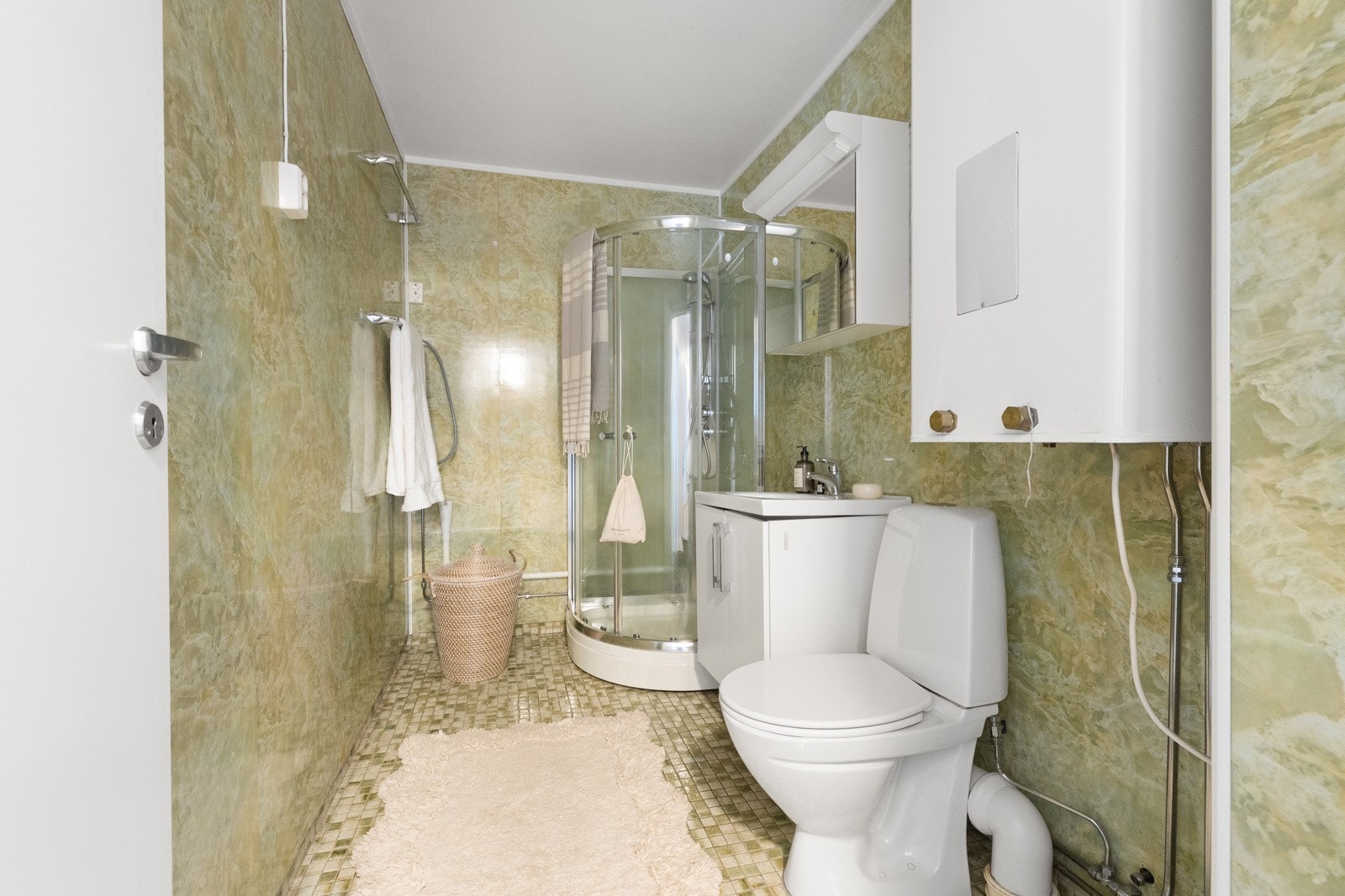 Badet er innredet med toalett, servant, speil, høyskap og dusjkabinett. Galleribilde