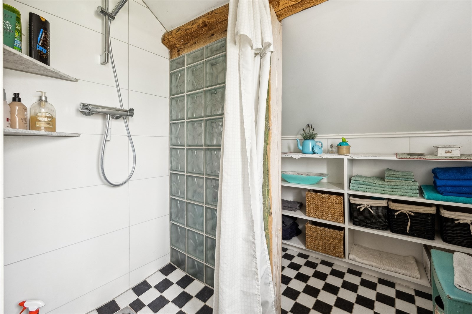 Flislagt baderom med dusjnisje direkte på gulv, avskjermet med dusjforheng. Galleribilde