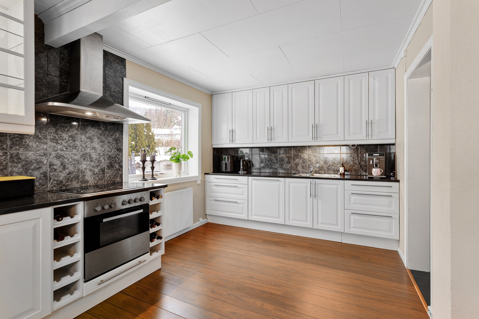 Lysarmaturer under overskap og flislagte felt på vegger over benkeplater av laminat Galleribilde