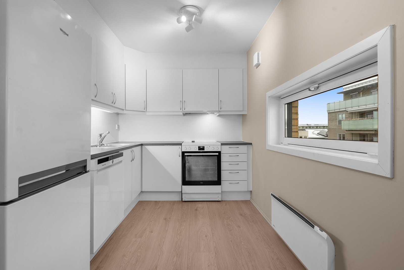 Kjøkkeninnredning med hvite, glatte fronter og laminat benkeplate. Galleribilde