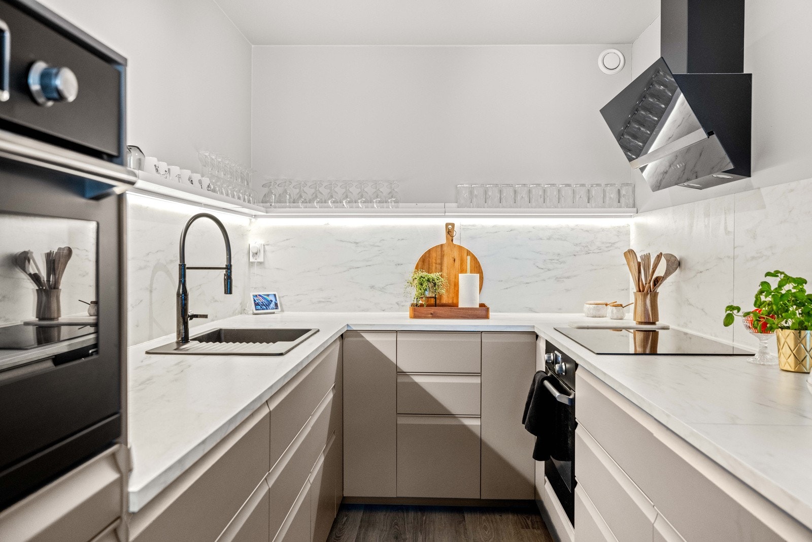 Et lekkert kjøkken med glatte fronter, innfelte håndtak og laminert benk med nedfelt kum i kompositt. Galleribilde