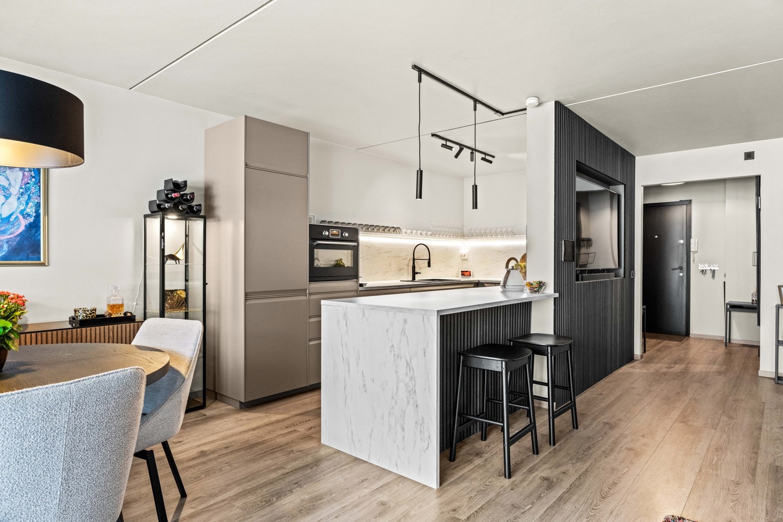 Strøkent drømmekjøkken fra 2023 i egen sone i bakkant av stuen. Galleribilde