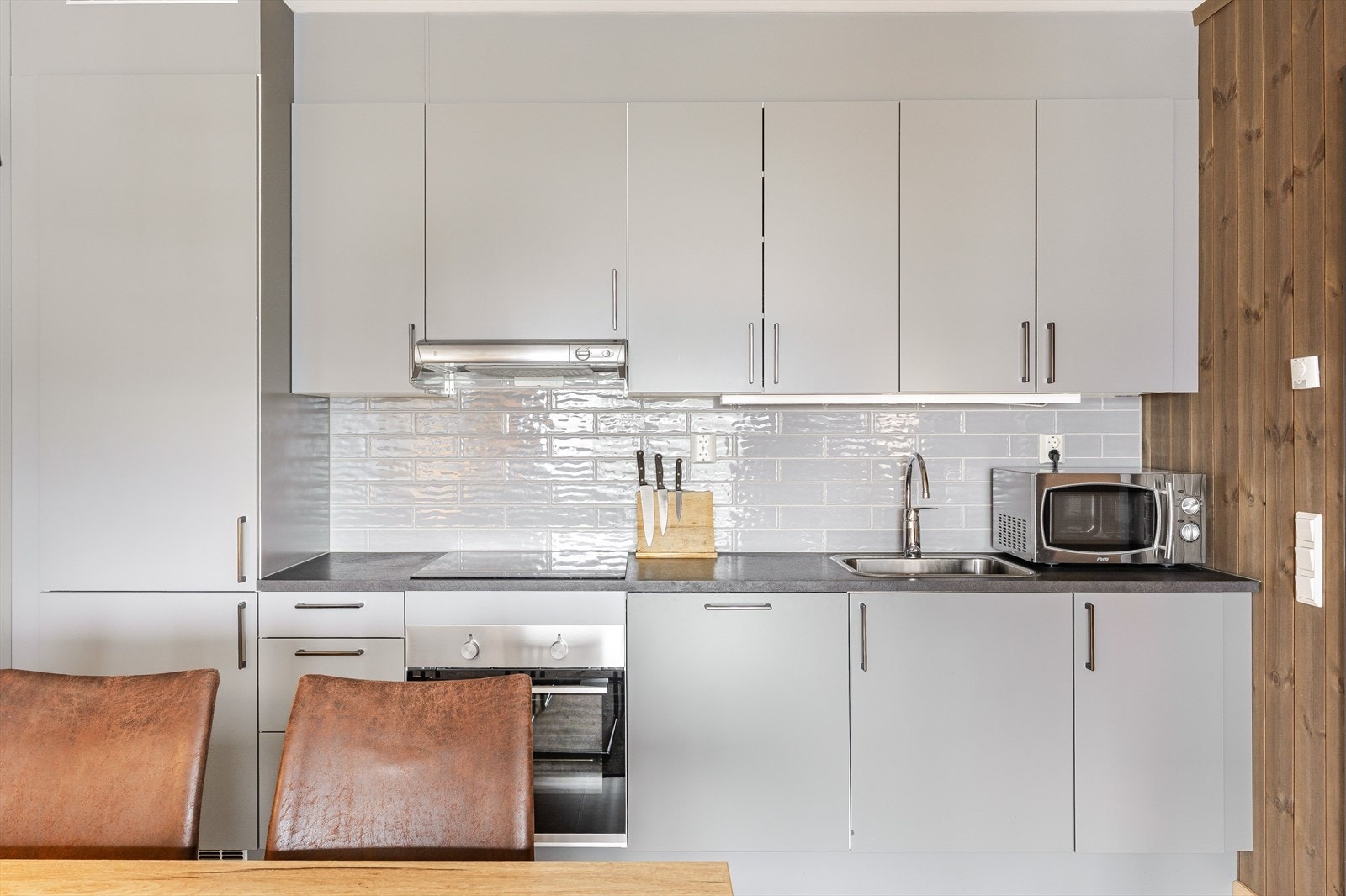 Innredningen har glatte fronter i en tidløs farge, laminert benkeplate med nedfelt oppvaskkum og fine fliser i benkeryggen. Praktisk med belysning under overskapene og og kjøkkenventilator med avtrekk. Galleribilde