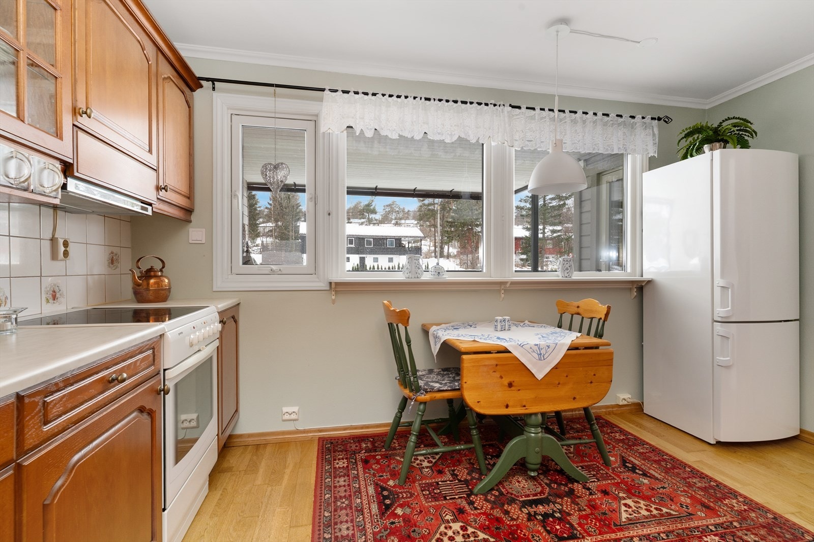 Hyggelig spiseplass ved kjøkkenvinduer. Overflater består av parkett på gulv, malt tapet på vegger og malt tak. Galleribilde