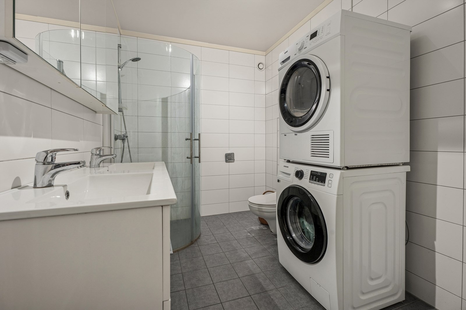 Det er også opplegg for vaskemaskin, praktisk plassert i rommet, samt plastsluk og mekanisk avtrekk som sørger for god ventilasjon. Dette er et bad med funksjonelle løsninger som legger til rette for en komfortabel og praktisk hverdag. Galleribilde