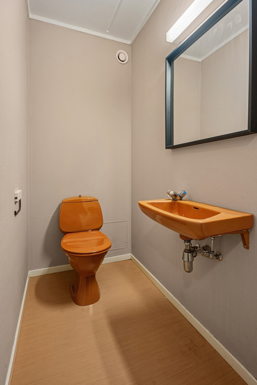 Toalettrommet er utstyrt med servant, speil med tilhørende belysning og et gulvmontert toalett. Dette gjør rommet funksjonelt og lett å holde rent - en praktisk løsning som kompletterer boligens øvrige baderom på en god måte. Galleribilde