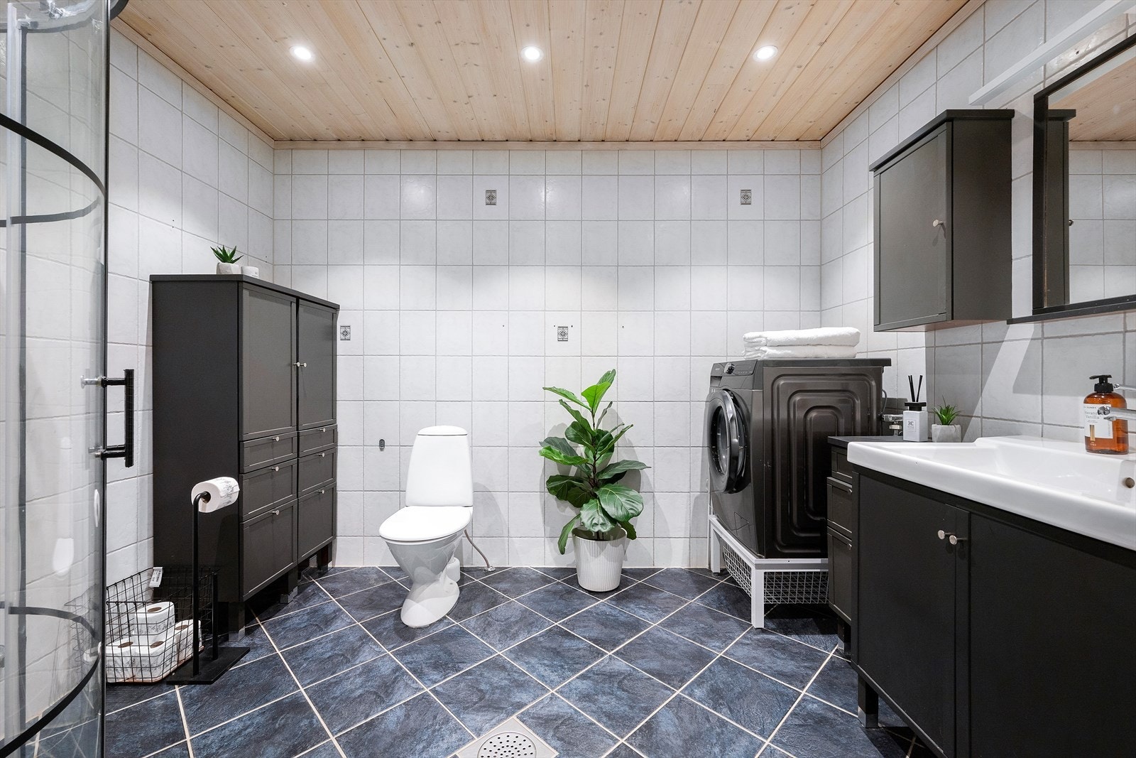 Badet er romslig med flislagt gulv, lyse flater og stiligedetaljer. Galleribilde