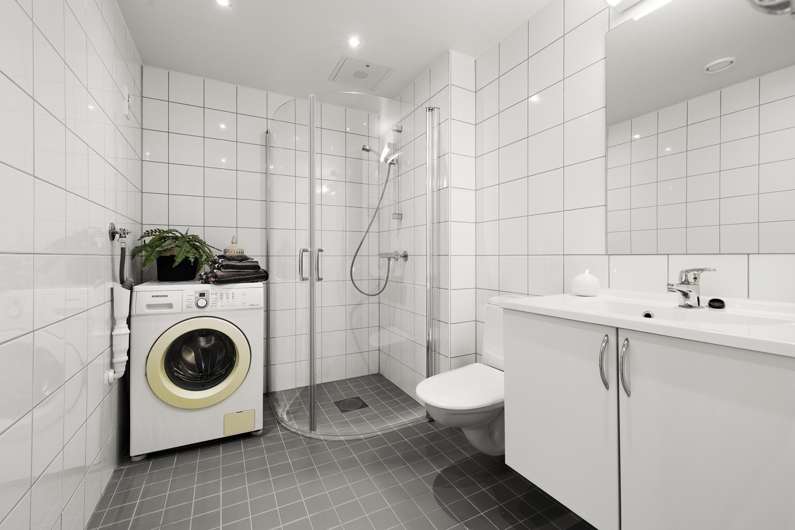 Flislagt bad med dusjhjørne og opplegg for vaskemaskin. Galleribilde