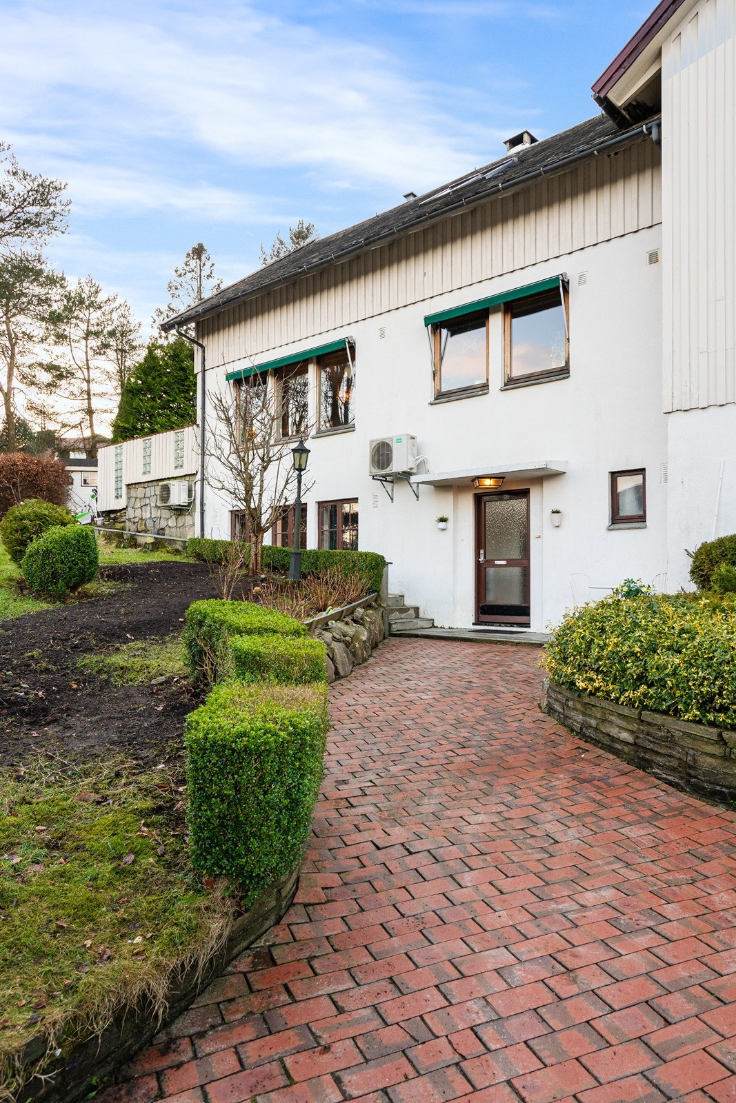 Inngangsparti er pent opparbeidet med beleggningsstein og beplantning. Galleribilde