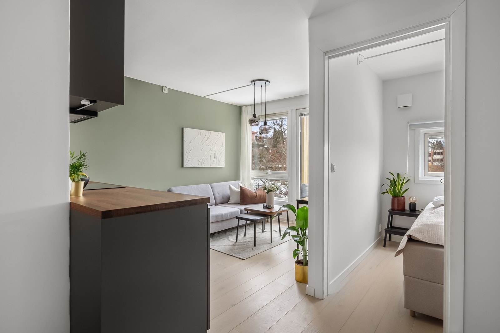 Stilrent IKEA-kjøkken fra 2024 med benkeplate i laminat samt elektronisk lekkasjestopper - Skyvedør inn til soverom. Galleribilde