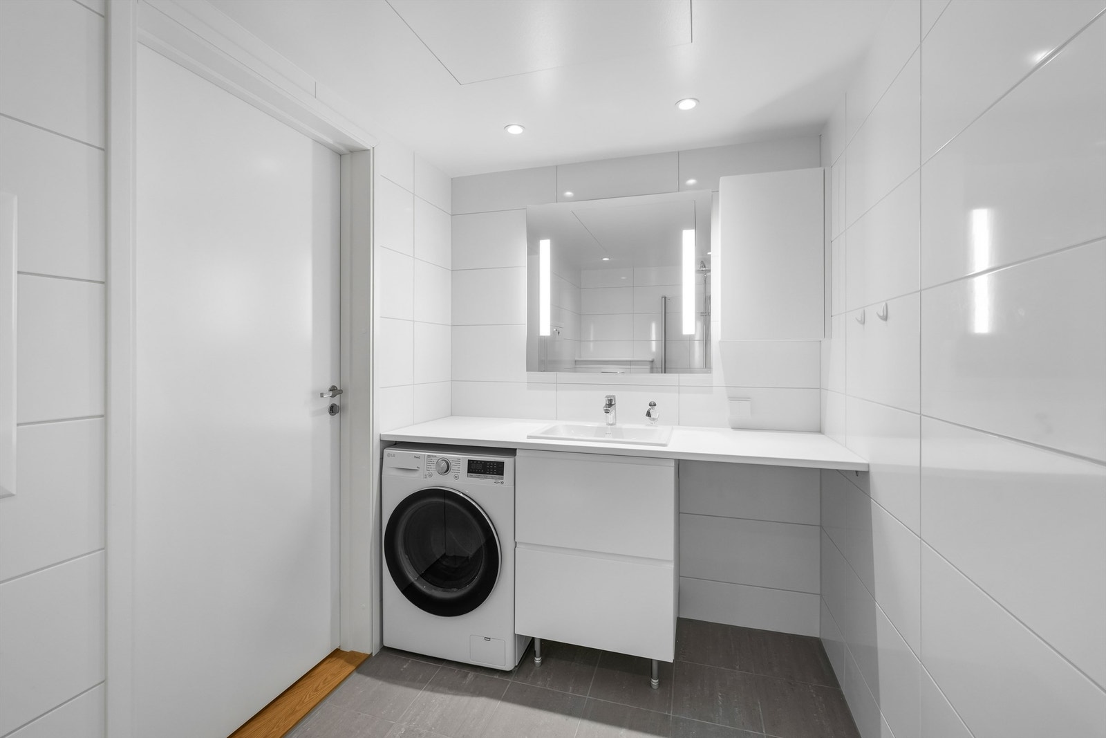 Bad med downlights og speil med innfelt belysning og praktisk nisje til vaskemaskin. Galleribilde