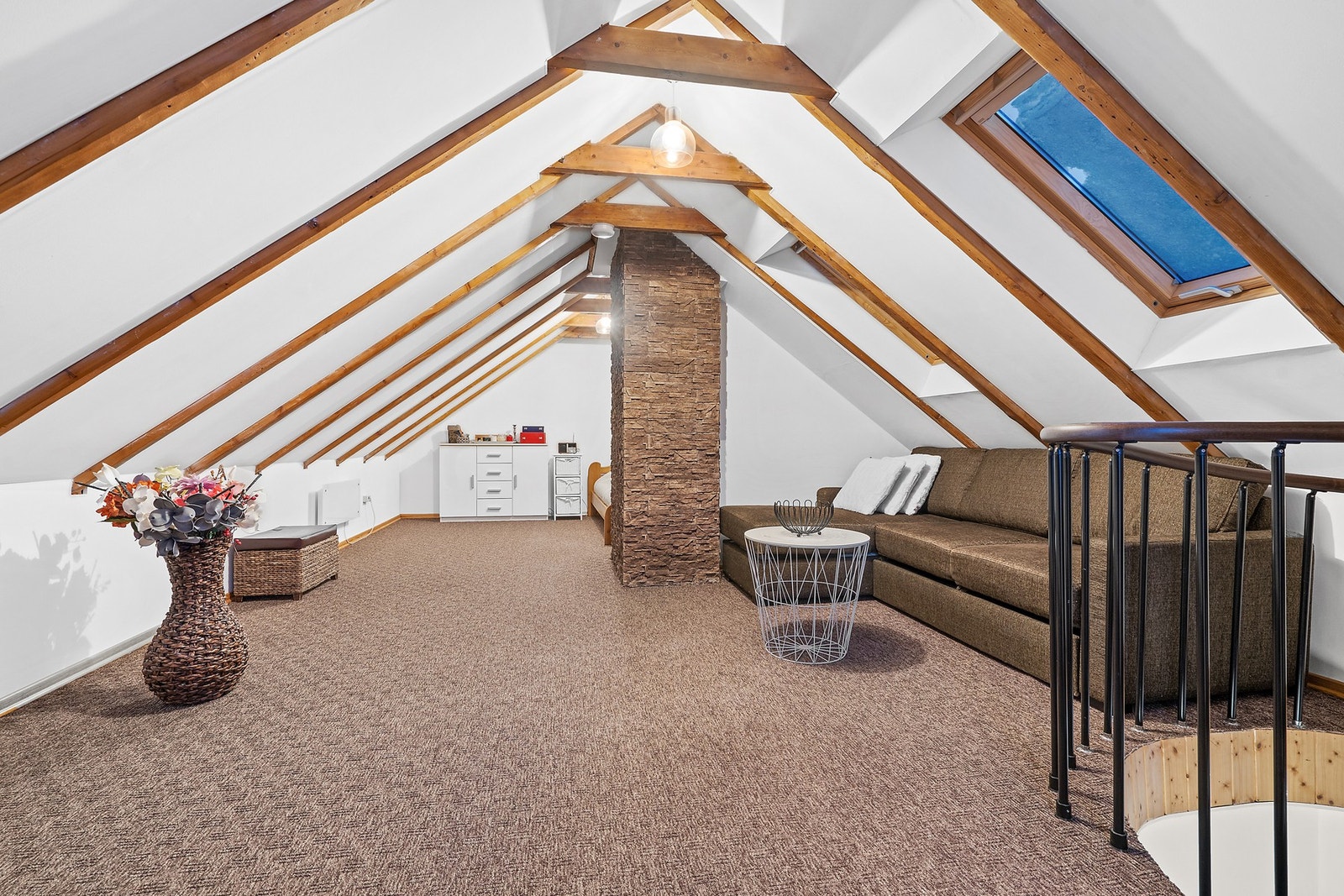 Synlige takbjelker og en kledd mursteinspipe gir rommet en rustikk karakter. Galleribilde