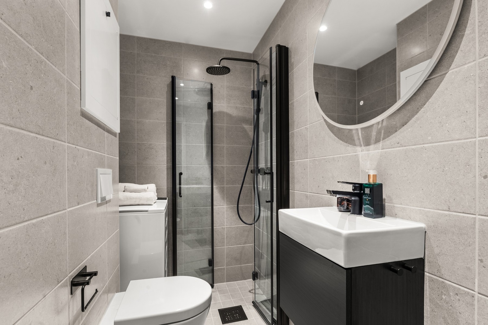 Badet er utstyrt med: Dusj med innfellbare glassvegger, servantseksjon med skap og heldekkende porselenvask, speil med lys, vegghengt WC samt opplegg for vaskemaskin. Galleribilde