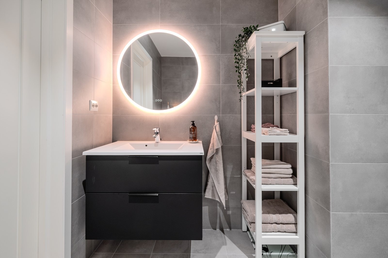 Lekkert belyst speil over heldekkende servant med skuffer Galleribilde