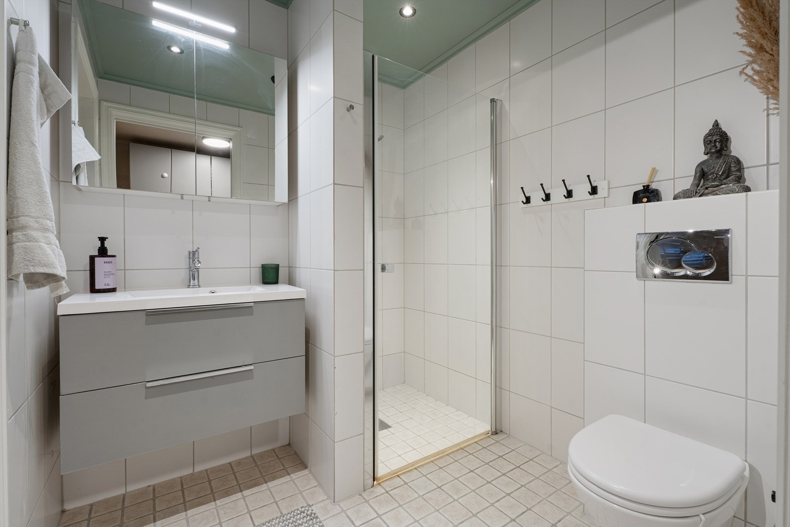 Rommet er utstyrt med en baderomsinnredning med servant og blandebatteri, speil, lys, dusjhjørne med glassdør og et vegghengt toalett. Galleribilde